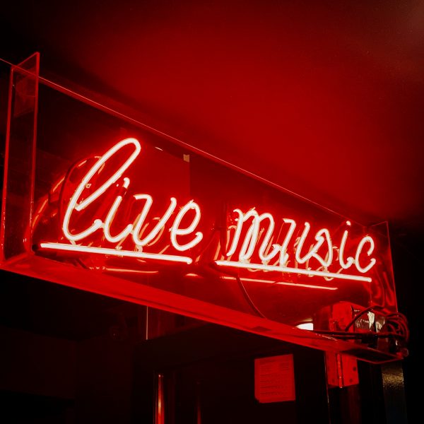 Red neon sign that says live music in cursive font