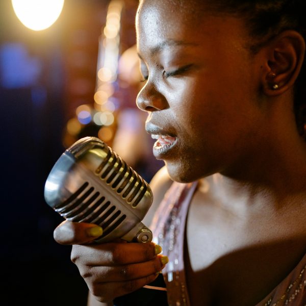 Woman singing into a microphone on stage with spotlight shining on her