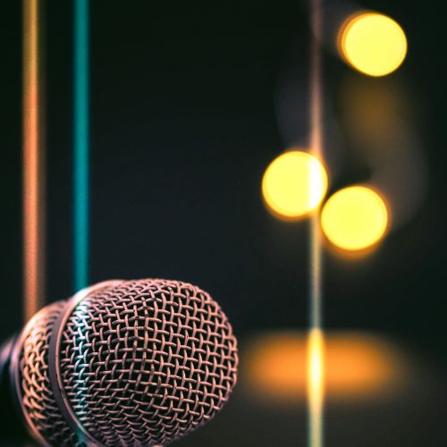 A vertical shot of a microphone with bokeh lights in the background