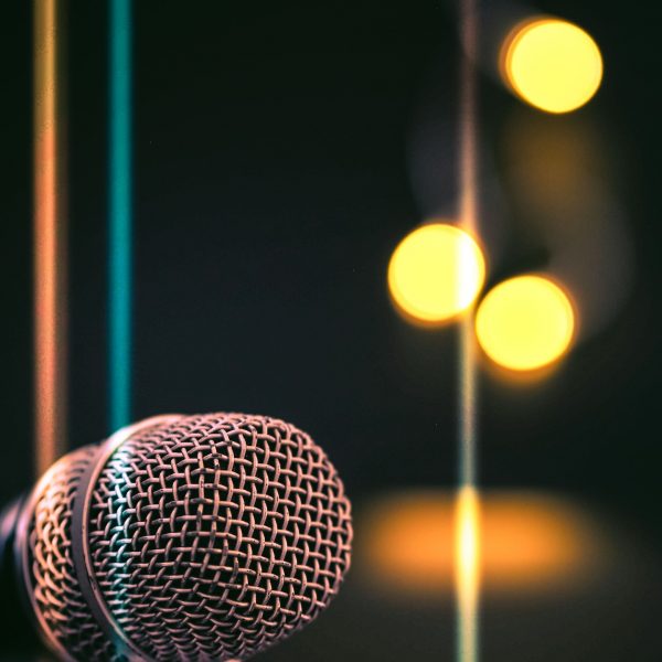 A vertical shot of a microphone with bokeh lights in the background