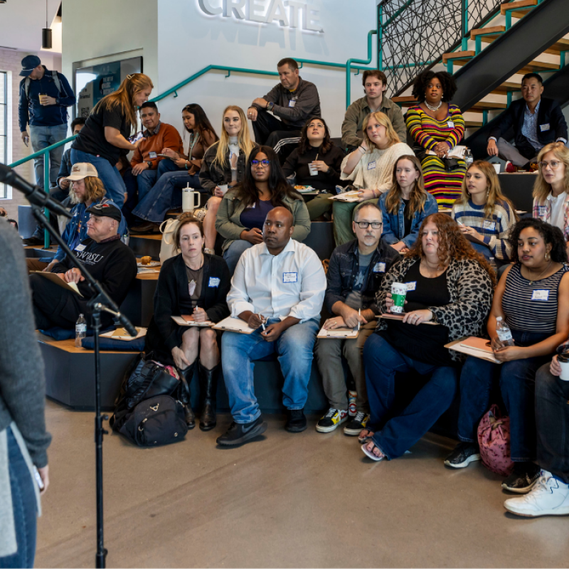 Artists and musicians at the 2025 Melody of Hope workshop listening to founder Charlie Welch speak
